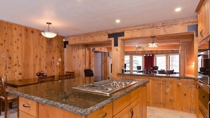 A kitchen with wooden walls, granite countertops, and a central island with a stove. - Tahoe Lodge Style Ambiance, Dog Friendly with Hottub, Sauna & Fenced Yard. By Tahoe Time VR (Tahoe City)