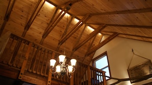 Un intérieur en bois agrémenté d’un lustre, d’une fenêtre et d’un panneau indiquant les règles à respecter au bord du lac.