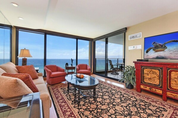 Un salon spacieux doté d’une grande fenêtre donnant sur la mer, d’un canapé confortable, d’une table basse et d’un téléviseur.