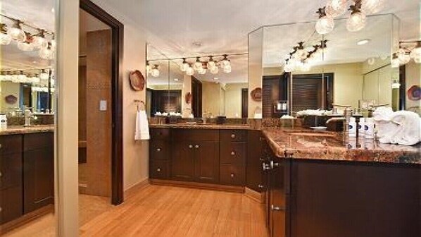 A modern bathroom with a large mirror, wooden cabinets, and a marble countertop.
