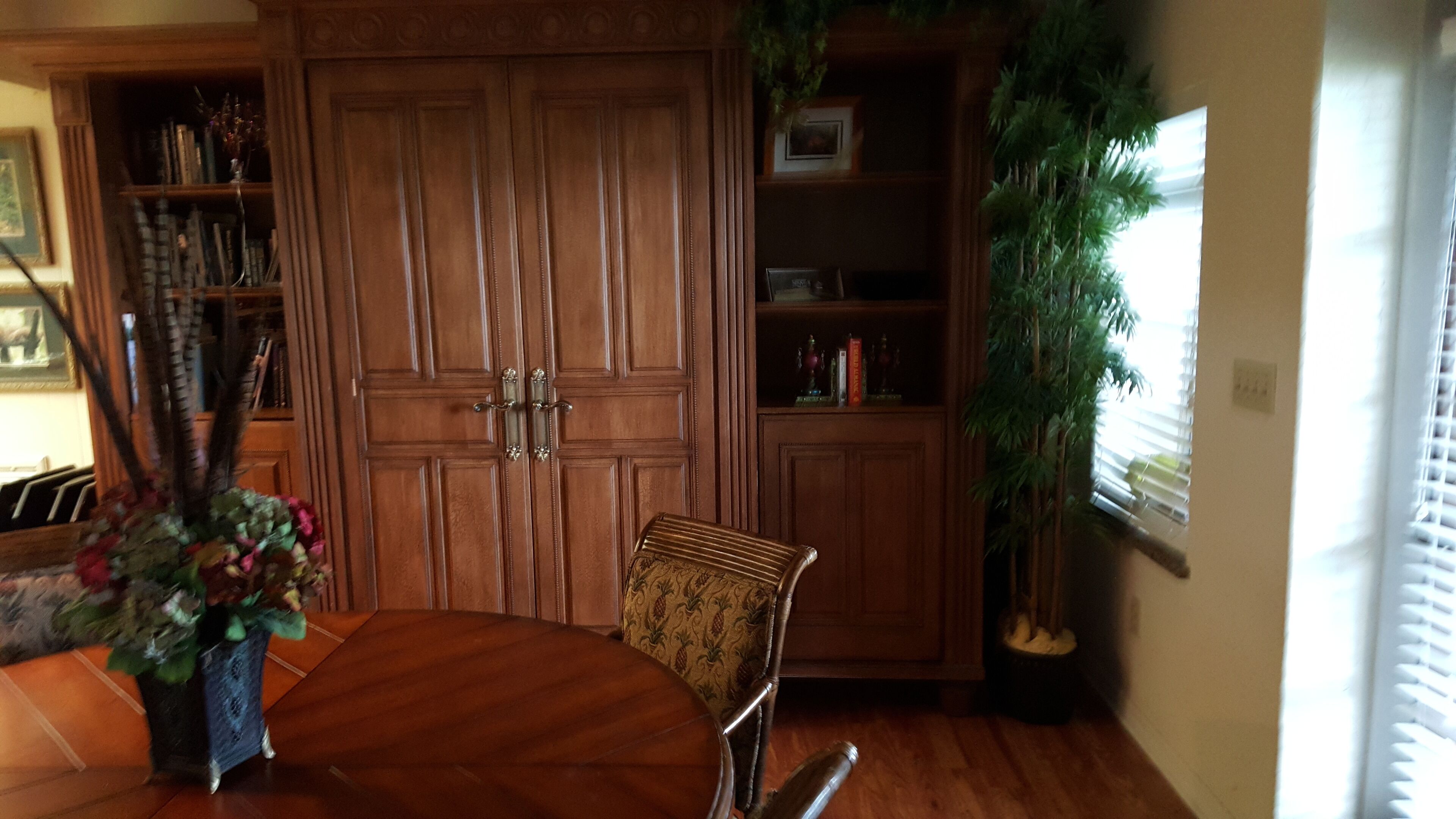Uma sala de jantar com uma mesa de madeira, cadeiras e uma estante.
