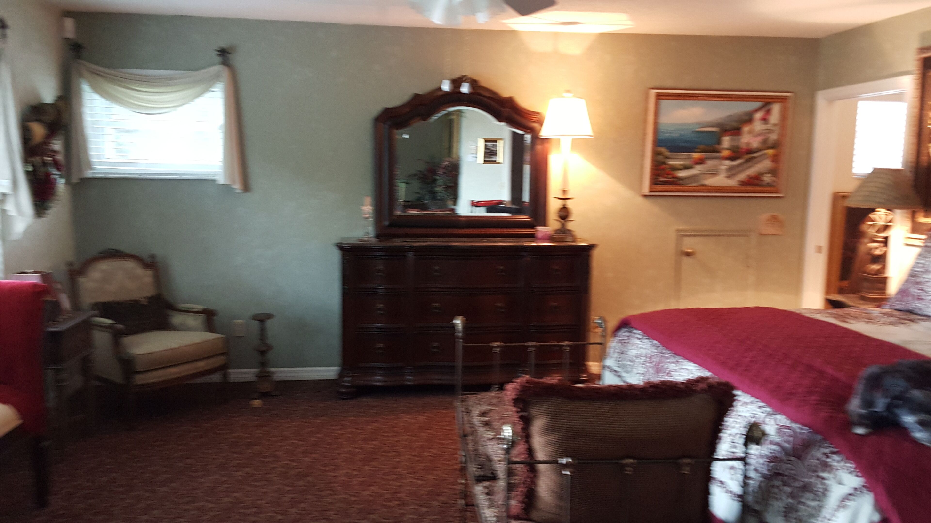 A bedroom with a bed, a dresser, a chair, and a mirror.