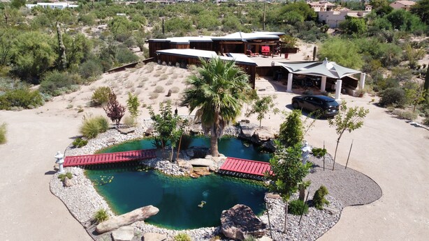 A large house with a swimming pool, surrounded by desert vegetation and a small bridge. - Family-Friendly Beautiful Private Wellness Retreat / Desert Oasis (Scottsdale)