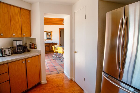 Una cocina con armarios de madera, un refrigerador de acero inoxidable y una encimera con cafetera y tostadora.
