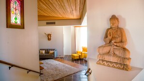 A room with a wooden ceiling, a Buddha statue, a stained glass window, a sofa, and a chair. - Family-Friendly Beautiful Private Wellness Retreat / Desert Oasis (Scottsdale)