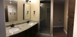 Une salle de bain avec deux lavabos, un grand miroir et une douche à l’italienne.