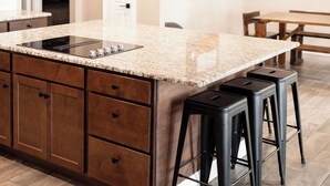 Una cucina moderna con un'isola grande, mobili in legno scuro e sgabelli da bar neri.