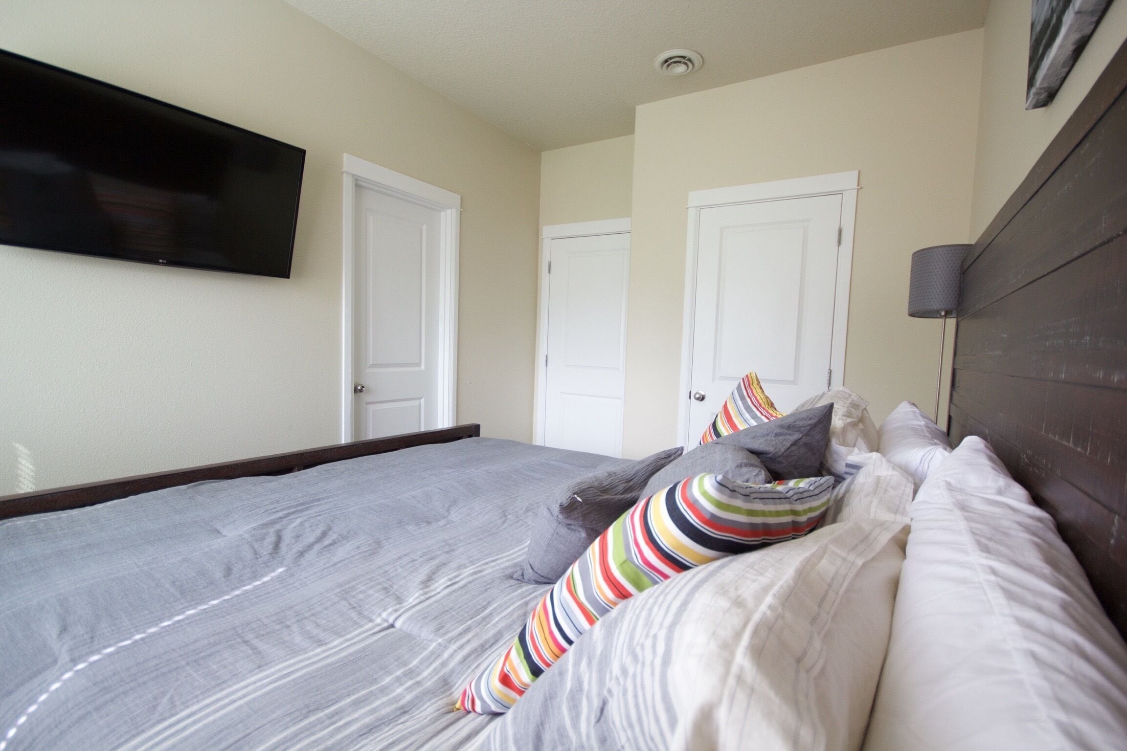 Une chambre à coucher avec un grand lit, deux portes, un téléviseur à écran plat et une lampe.