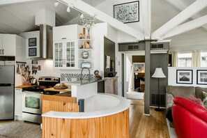 A modern kitchen with a central island, a dining area with a red sofa, and a living room with a lamp. - SeaLoft in the woods, close to the beach.  (Hilton Head Island)