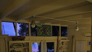 Tilava olohuone, jossa on korkea katto, useita ikkunoita ja portaikko, joka johtaa ylemmälle tasolle.