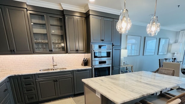 A modern kitchen with dark cabinets, a marble island, and wicker bar stools. - Gulf-front,Pool,Balcony, VIEWS, 30A, Private Beach, Grill (Santa Rosa Beach)