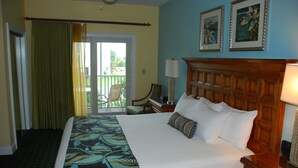A hotel room with a large bed, a wooden headboard, a desk with a lamp, a chair, and a balcony with a view. - South Beach Resort-Beautiful Beach Resort for Family Fun!! (Myrtle Beach)