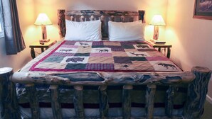 A bed with a quilt featuring animal prints, flanked by two nightstands with lamps, a wooden headboard, and a sign above the bed. - Mountain and River Views, Seasonal Pool, Near National Park (Estes Park)