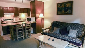 A compact living space with a kitchenette, a sofa, a coffee table, and a painting on the wall. - Mountain and River Views, Seasonal Pool, Near National Park (Estes Park)