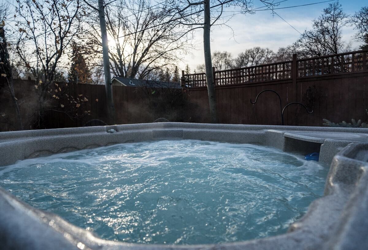A hot tub surrounded by a wooden fence and trees.