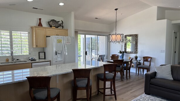 A spacious kitchen with a large island, wooden chairs, and a dining area with a chandelier. - Upscale all the Way! 2BR 2BA Las Palmas Condo in St. George UT (St George)