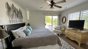 A bedroom with a bed, a ceiling fan, a TV, a dresser, and a balcony with a chair. - Upscale all the Way! 2BR 2BA Las Palmas Condo in St. George UT (St George)
