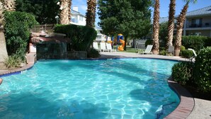 A swimming pool with clear blue water, surrounded by palm trees and lounge chairs. - Upscale all the Way! 2BR 2BA Las Palmas Condo in St. George UT (St George)