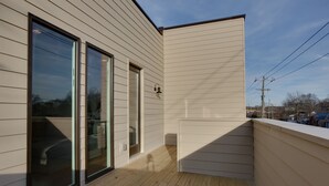 A modern building with large sliding glass doors, a wooden deck, and a clear sky. - Music Centric Home, 5 minutes to Broadway. (Nashville)