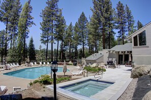 Un espace piscine avec des chaises longues, un jacuzzi et un bâtiment doté d’une terrasse.