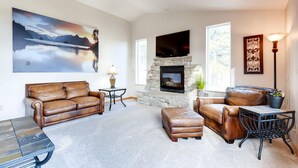 A living room with a stone fireplace, leather sofas, a coffee table, and a TV mounted on the wall. - 2 KING Masters, Pikes Peak Views.  Sleeps 17, Close To AF Academy - 2 Living Rms (Colorado Springs)