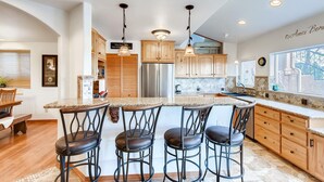 A modern kitchen with a central island, bar stools, wooden cabinets, stainless steel appliances, and pendant lighting. - 2 KING Masters, Pikes Peak Views.  Sleeps 17, Close To AF Academy - 2 Living Rms (Colorado Springs)