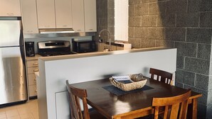 A modern kitchen with a central island, wooden dining table, and chairs. - Architectural dream guest house (Phoenix)