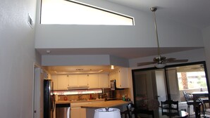 Une cuisine moderne avec des meubles blancs, des appareils en acier inoxydable et un coin repas comprenant une table et des chaises.