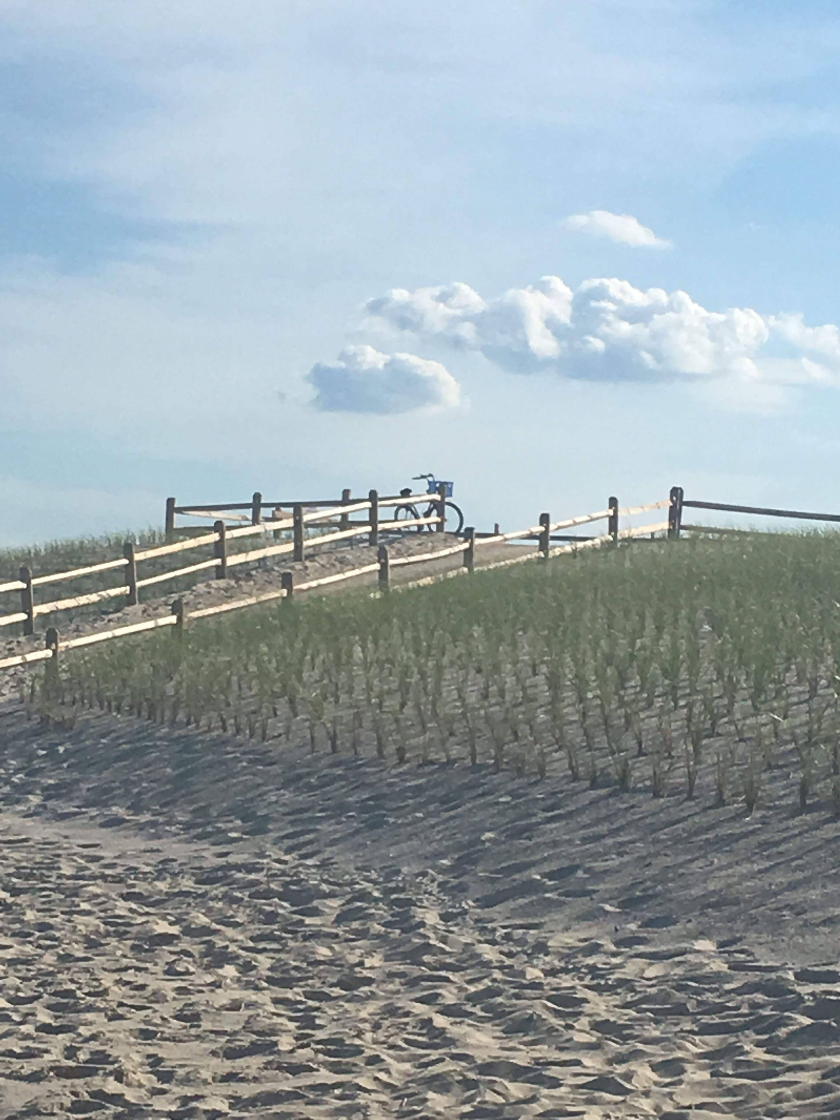 Ein sandiger Strand mit einer Holzlattenveranda und einem Fahrrad.