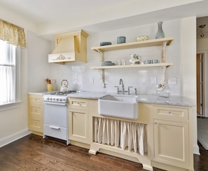 A kitchen with a stove, sink, and cabinets. There are shelves above the sink with dishes and a vase. - Romantic, Way Better than Hotel - Block from Beach Free Wifi - Enhanced Cleaning (Ocean Grove)