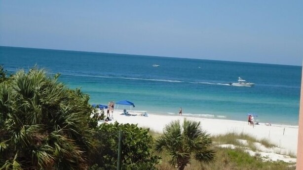 A beach with clear skies, a sandy shore, and a few people and boats. - SPECTACULAR BEACH CONDO. 2/2 PLUS DEN. HEATED POOL - EMAIL US. (Indian Shores)