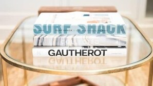 A glass-top table with a wooden tray and a box labeled "SURF SHACK" and "GAUTHEROT." - Playa One Bedroom (251) (Carpinteria)