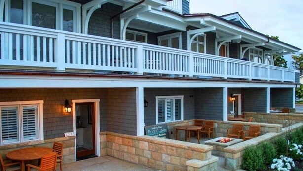 A two-story building with a balcony and outdoor seating area. - Playa One Bedroom (251) (Carpinteria)