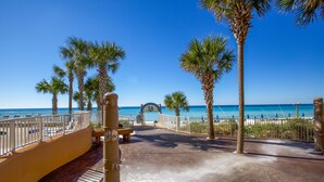 A paved walkway with palm trees and a beach view. - Corner Condo - Stunning Gulf Views -Comp. Beach Service, Water Park & Lazy River (Panama City Beach)