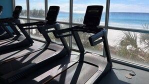 A gym with treadmills positioned near large windows overlooking a beach. - Corner Condo - Stunning Gulf Views -Comp. Beach Service, Water Park & Lazy River (Panama City Beach)