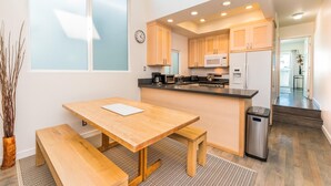 A modern kitchen with wooden cabinets, a microwave, and a stainless steel refrigerator. - Cool Coastal Tri-Level Condo with Ocean Views! (Newport Beach)
