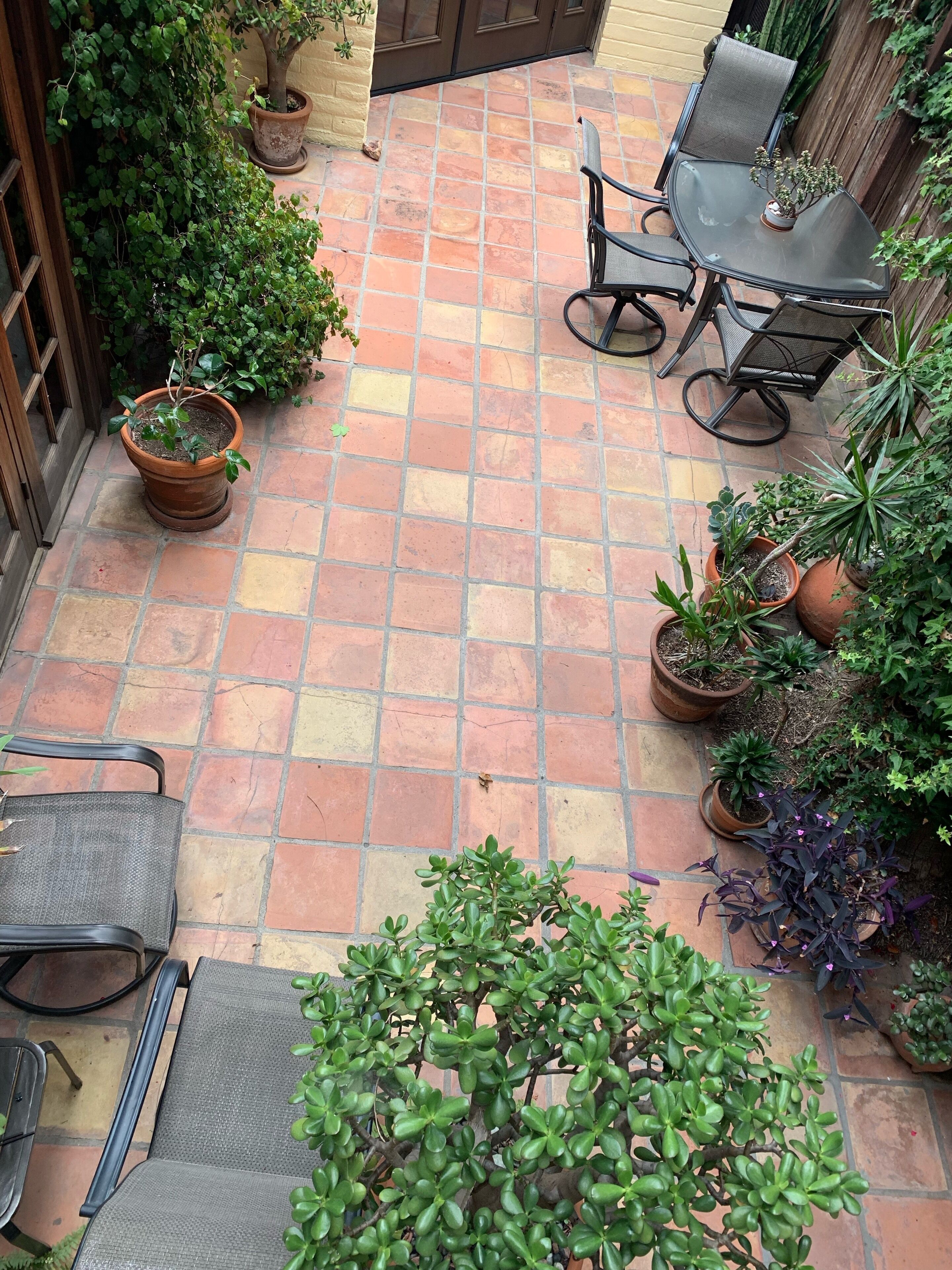 A patio area with tiled flooring, potted plants, and outdoor furniture.