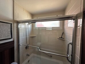 Een bad/douchecombinatie, een haardroger, handdoeken, zeep