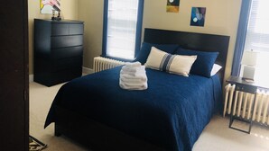 Une chambre avec un grand lit, une commode, un radiateur et des œuvres d’art accrochées aux murs.