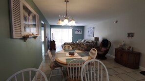 Un espace repas comprenant une table ronde, des chaises blanches, un lustre, un canapé et un buffet.