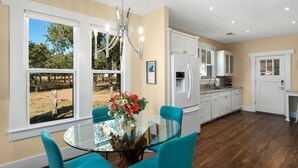 Une cuisine moderne avec des meubles blancs, une table à manger en verre et des chaises de couleur turquoise.
