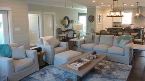 A spacious living room with a ceiling fan, a dining area, and a kitchen in the background. - Book now for 2026 (Orange Beach)