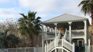 A pool with a white deck, a covered seating area with railings, and palm trees in the background. - Book now for 2026 (Orange Beach)