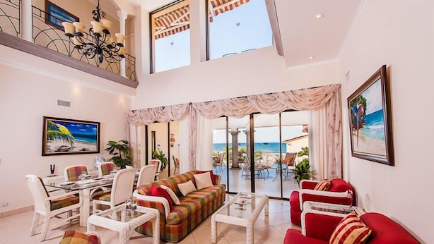 A spacious living room with a high ceiling, a dining area, and a view of the sea through large glass doors. - Two Story, 5 Bedroom Penthouse On Tamarindo Beach- New  (Tamarindo)