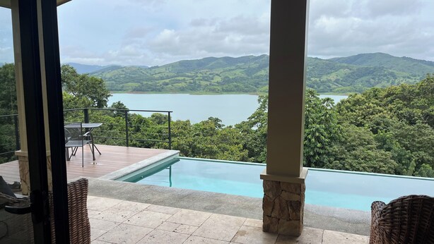 Zona de piscina con vistas a un lago y colinas.