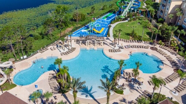 Ein Resort mit großem Schwimmbad, Wasserpark und angelegter Grünfläche mit Liegestühlen.