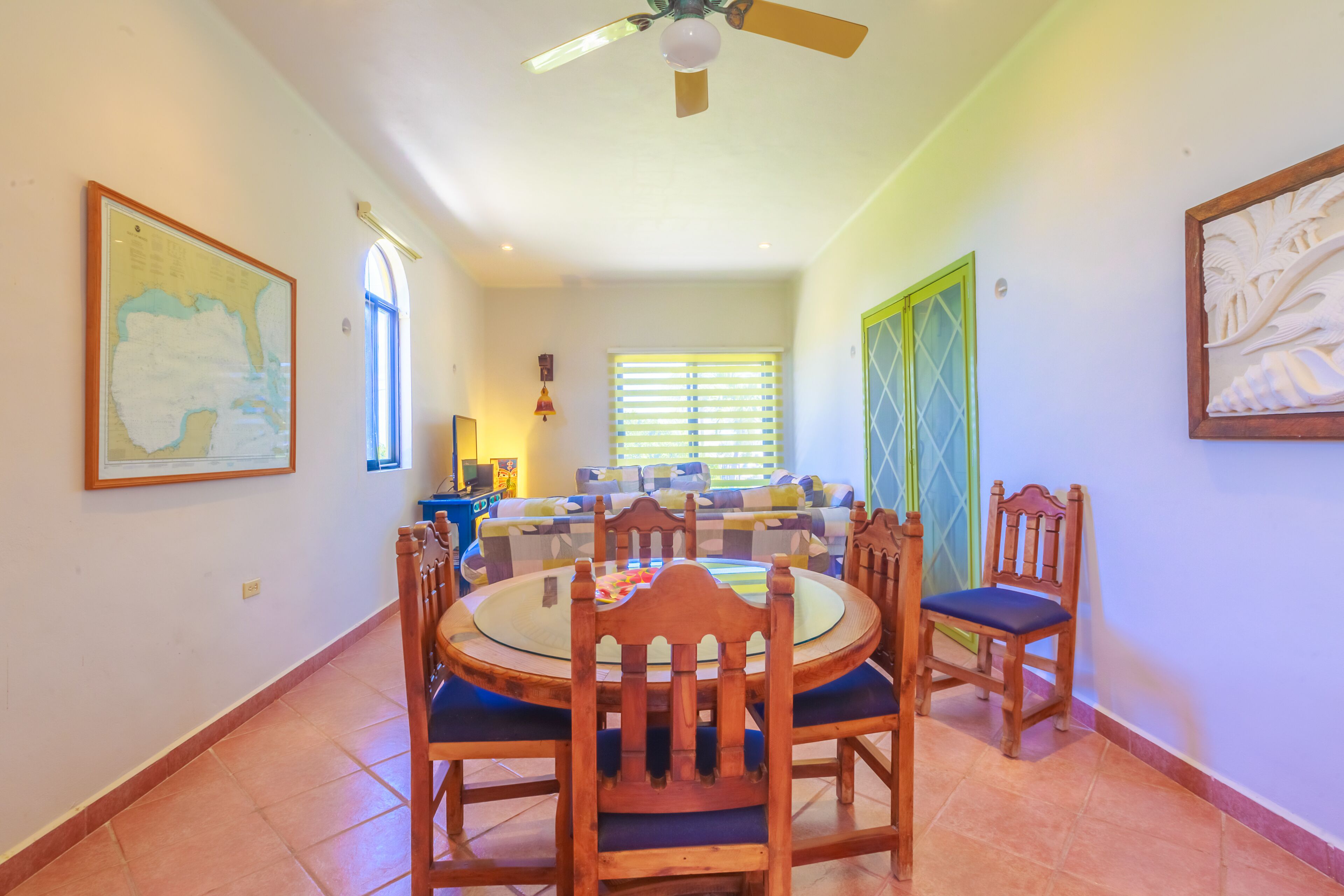 A dining area with a round table and chairs, a ceiling fan, and a window with blinds.