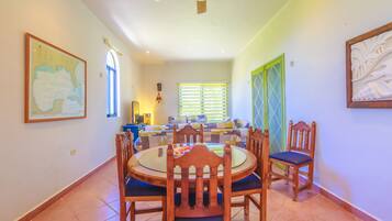 A dining area with a round table and chairs, a ceiling fan, and a window with blinds.