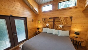 Un dormitorio con una cama grande, dos mesitas de noche con lámparas, un cabecero de madera con adornos de estrellas y una ventana.