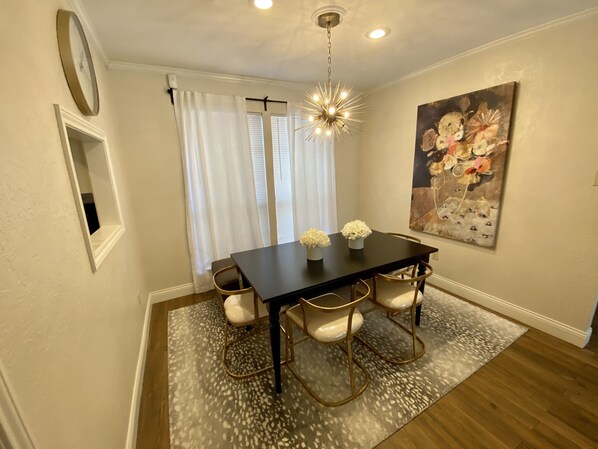 Un coin repas avec une table en bois foncé, des chaises blanches et un tapis à motifs.